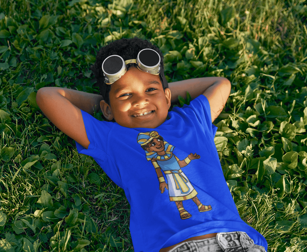 Black boy wearing Tut “Lead With Wisdom” T-shirt from TL Johnson’s Mini Monarchs Apparel; African royalty design for kids and families.