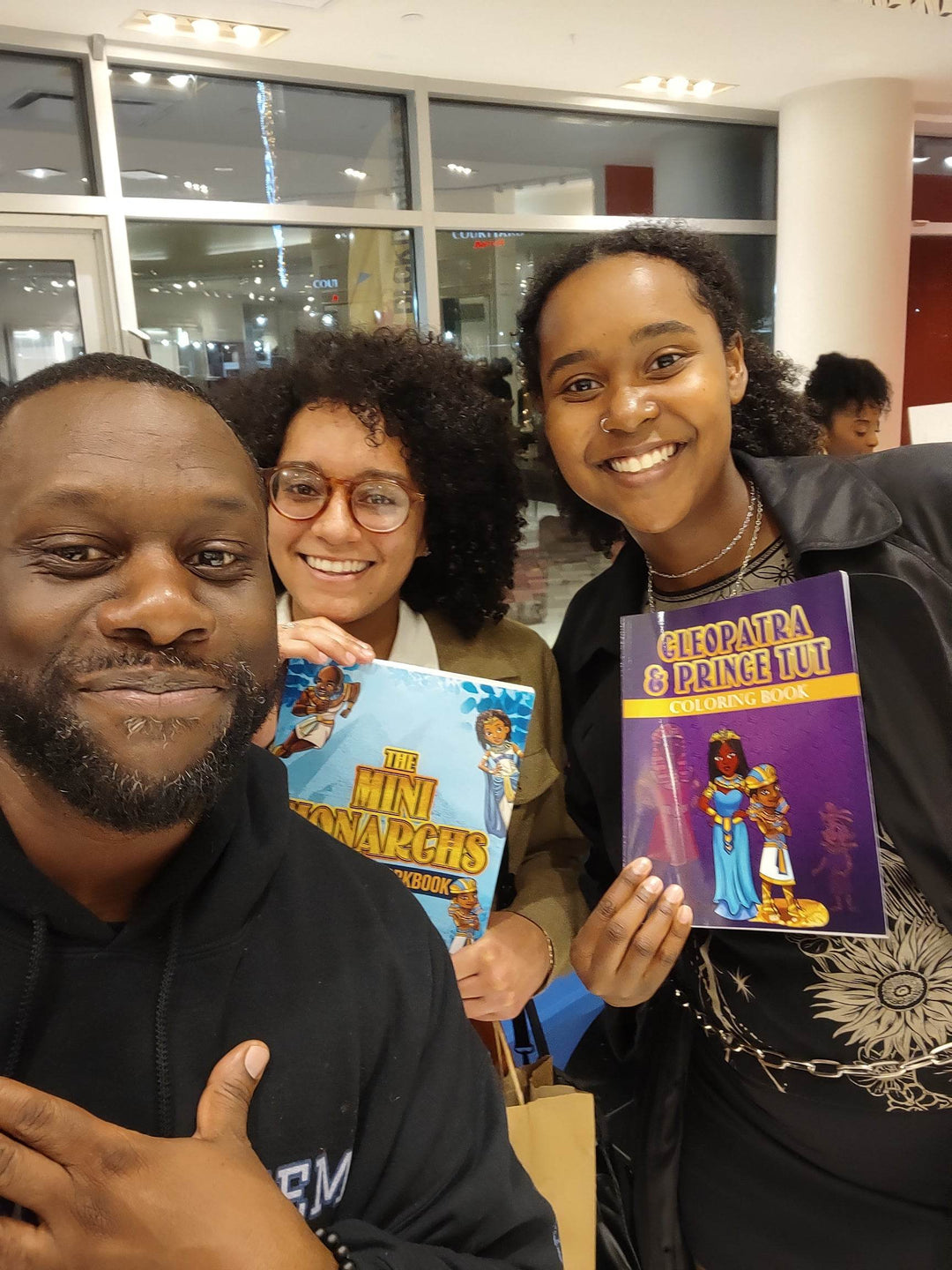 Tow young ladies with the creator one is holding The Mini Monarchs Activity Book. the other is holding Cleopatra & Tut Coloring Book.